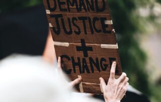 a person holding a sign that says we demand justice and change