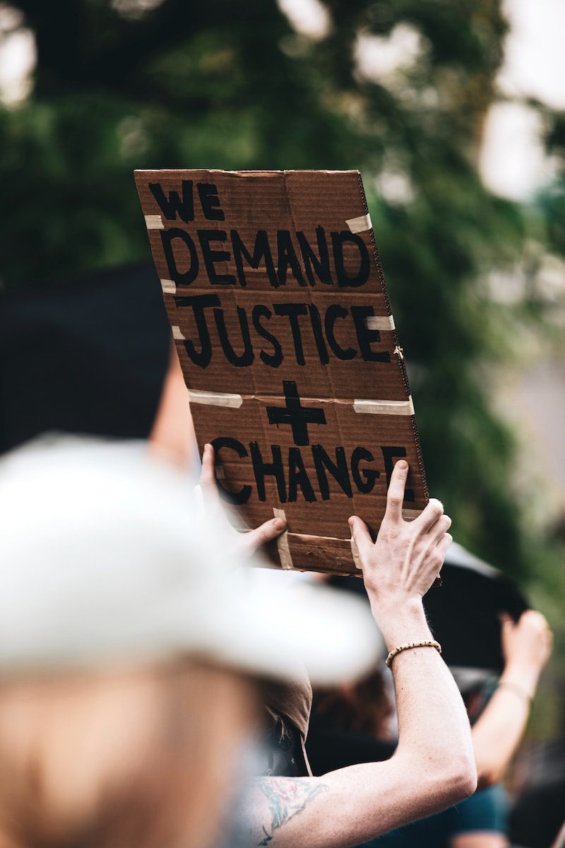 a person holding a sign that says we demand justice and change